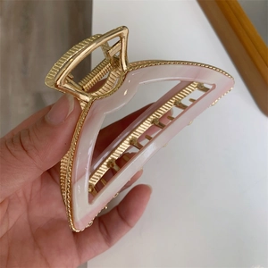 Detail of pink marble acrylic hair claw clip with a golden metal frame and strong spring