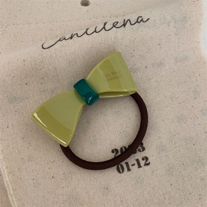 Detail of green bow hair tie with Amon Rose branding on high-elasticity band