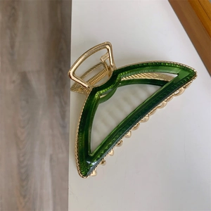 Detail view of the elegant golden metal frame with dark green resin hair claw clip detail