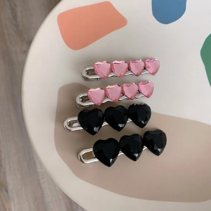 Dettaglio di fermagli per capelli a forma di cuore rosa e nero su piatto ceramico