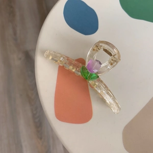 Nahaufnahme einer Acryl-Haarklammer mit lila Tulpe und grünem Blatt auf weißem Tisch