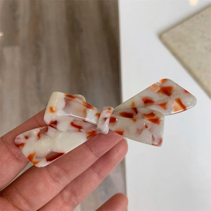 Vue détaillée d'une barrette à cheveux en acétate avec motif écaille et nœud chic