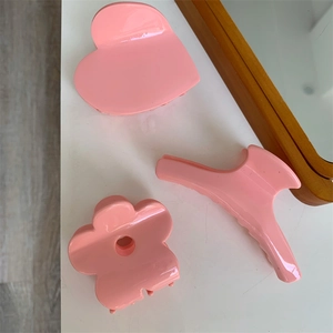 Set di mollette per capelli rosa a forma di cuore e fiore su superficie bianca