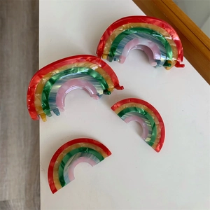 Close-up of rainbow acetate hair clips in various sizes on a clean white surface
