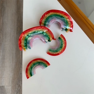 Detailed view of rainbow acetate hair claws with colorful marble texture on white surface