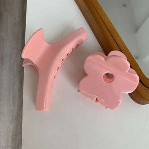Dettaglio molletta per capelli a fiore rosa e clip a mezzaluna su tavolo bianco