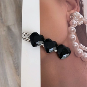 Dettaglio della molletta per capelli nera con triplo cuore e decorazioni in resina