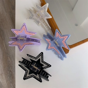 Detail view of four acetate star hair claws in ivory, purple, blue and black with rhinestones