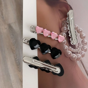 Dettaglio di fermagli per capelli a cuore rosa e neri con struttura a becco e cristalli