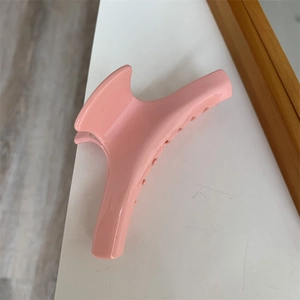 Dettaglio ravvicinato di una pinza per capelli rosa in acetato con fiore e cuore