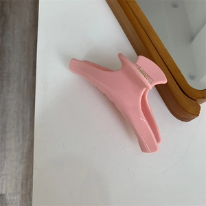 Dettaglio molletta per capelli rosa in acetato con finitura lucida e molla in metallo