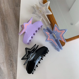Detail view of four star-shaped acetate hair claws with sparkling rhinestones in assorted colors