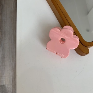 Dettaglio di un fermaglio per capelli a forma di fiore rosa su sfondo bianco pulito