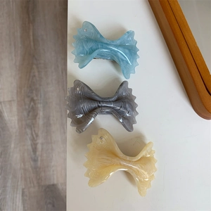 Close-up of marble pattern acetate hair clips with bow design and small rhinestones