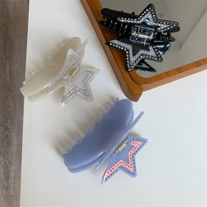 Detailed view of three star-shaped acetate hair claws with sparkling rhinestone accents