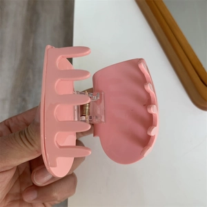 Dettaglio della pinza per capelli rosa opaco con molla in metallo e denti incrociati