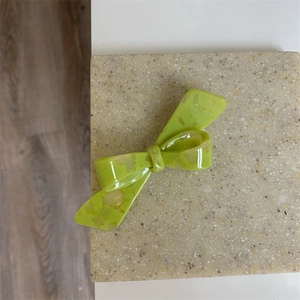 Détail d'une pince à cheveux verte en acide acétique avec un motif de nœud marbré