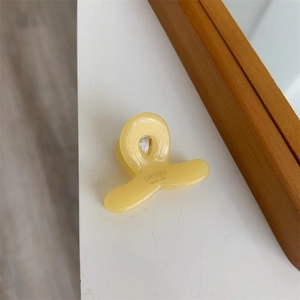 Détail d'une petite pince à cheveux en acétate jaune clair avec texte Sunshine