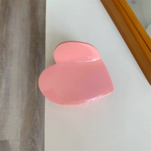 Dettaglio della pinza per capelli rosa a forma di cuore con finitura lucida su tavolo