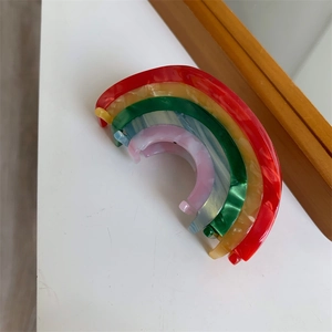Macro shot of five colorful marble-patterned acetate hair clips in a nested rainbow set