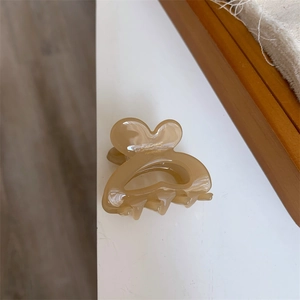 Macro detail of amber acetate rabbit ear hair clip showing the gold handmade logo