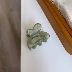 Detail shot of light green translucent butterfly hair claw clip on a natural canvas background