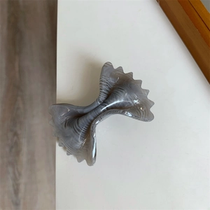 Close-up of acetic acid hair clip with marble pattern and wavy bow design texture