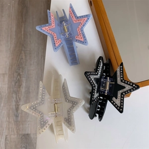 Detail of star-shaped acetate hair claws with sparkling rhinestones in three colors