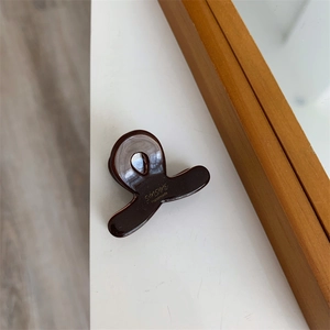 Détail macro de la pince à cheveux en acétate marron ambre avec lettrage SUNSHINE doré