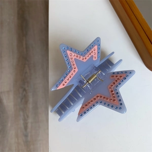 Detail of star-shaped acetate hair claw clip with purple body and sparkling rhinestones