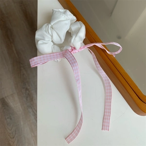 Detailansicht von weißem Scrunchie mit rosa karierter Schleife auf Holzoberfläche