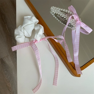 Detailaufnahme von rosa Schleifen-Haargummis und Perlen-Haarspange auf weißem Tisch