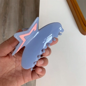 Close-up of light blue acetate hair claw clip with pink star accents and wide teeth