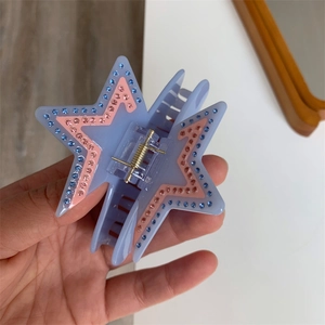 Close-up of star-shaped acetate hair claw with blue and pink rhinestones