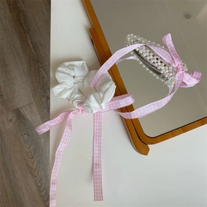 Detail von rosa kariertem Haargummi und Perlen-Haarspange-Set auf einem Spiegel