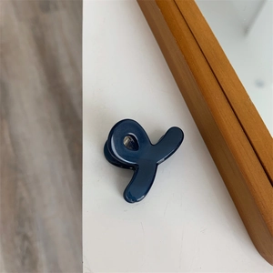 Détail d'une petite pince à cheveux bleu foncé au design circulaire artistique
