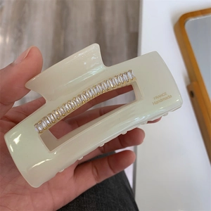 Gros plan sur la pince à cheveux en résine crème avec cristaux et logo France Handmade