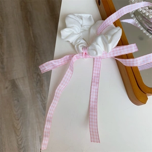 Detail von rosa karierter Schleife und weißem Satin-Scrunchie-Haar-Accessoire