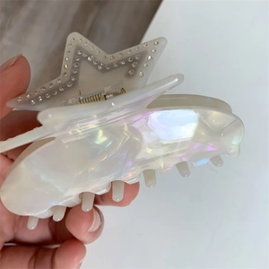Macro detail of iridescent white acetate star hair claw clip with pavé rhinestone edges