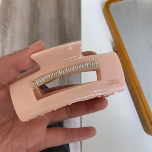 Détail de la pince à cheveux en acétate rose avec strass et lettrage doré France Handmade