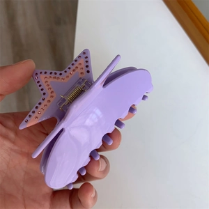Detailed view of a purple acetate star hair claw clip with inlaid sparkling pink rhinestones