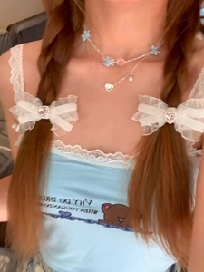Detail view of double-layered necklace with heart pendant and white lace bow hair clips