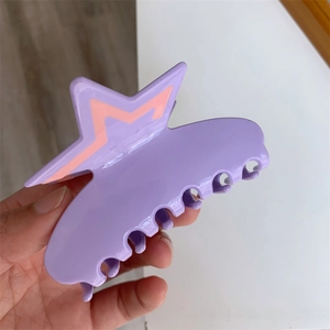 Close-up of a purple acetate claw clip featuring an orange star and rhinestone details