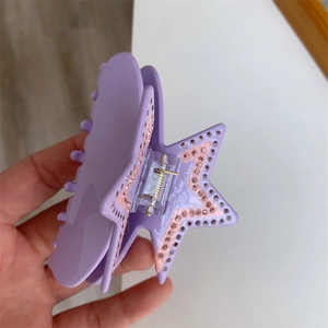 Close-up of star-shaped lilac acetate hair claw clip with rhinestones and metal hinge