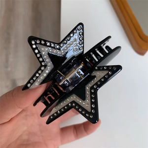 Close-up of a black star-shaped acetate hair claw clip with shiny white rhinestones