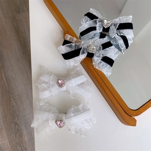 Close-up of four lace bow hair clips with heart-shaped rhinestones on a white table
