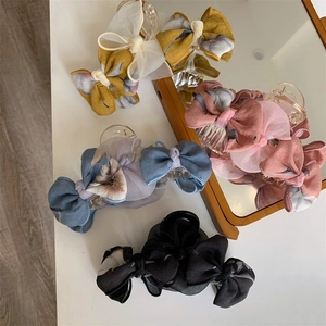 Vue détaillée de quatre pinces à cheveux avec nœuds floraux en jaune, rose, bleu et noir