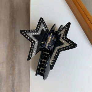 Close-up of a star-shaped acetate hair claw clip with rhinestones in black and white