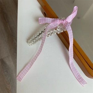 Handgefertigte rosa Haarklammer mit Schleife, weißen Perlen und Perlen auf weißem Tisch