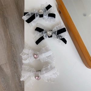 Detail of four lace bow hair clips featuring heart rhinestones and ribbon textures